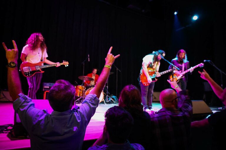 Audience and musicians in dark theater.