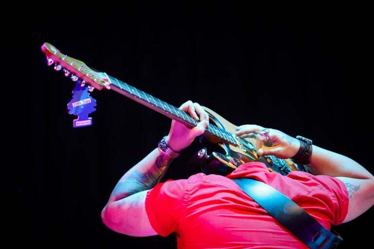 Musician playing guitar behind his head