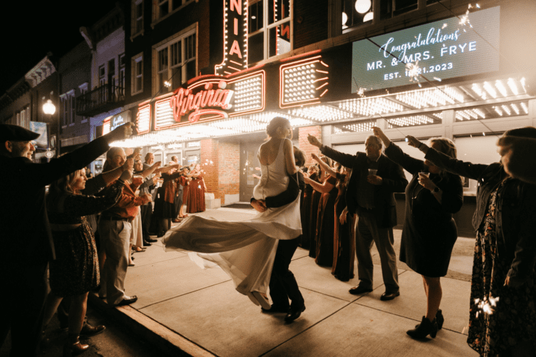 Bride and groom embracing outside the Virginia Theater with well wishers cheering