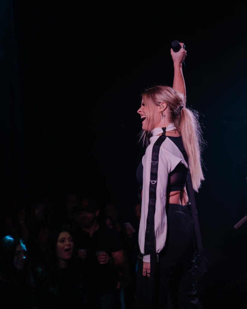 Woman on stage holding a microphone above her head