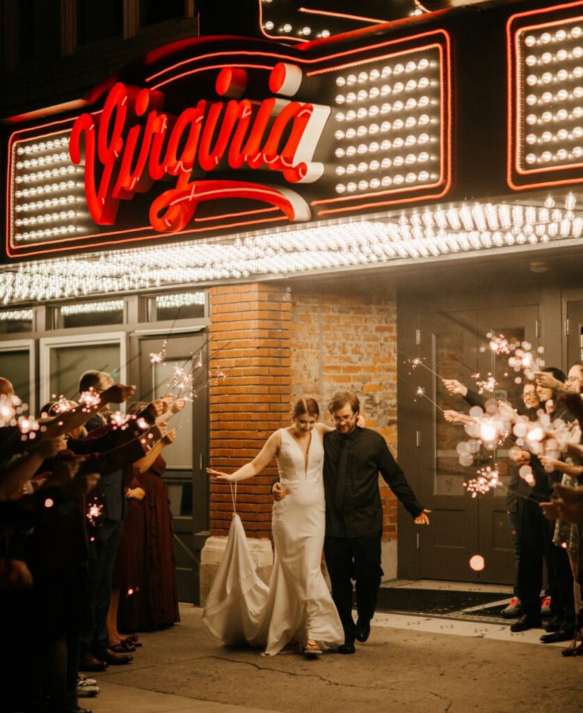 Wedding couple exiting the Virginia under lite marquee with people waving sparklers