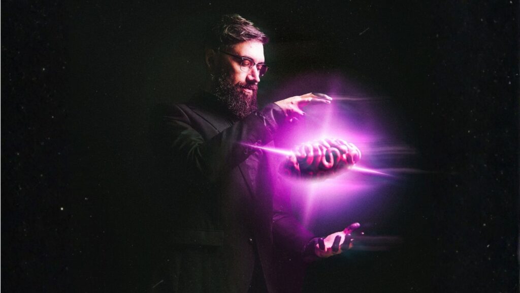 a man holding his hands wide vertically with a pink glowing brain suspended between them